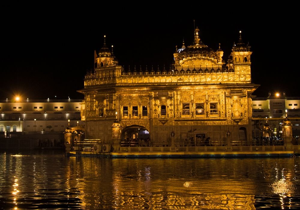 The Golden Temple lit up at night and reflected in the water
