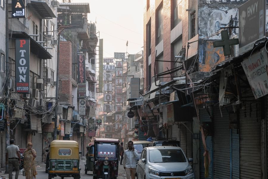 A narrow old-city street crowded with auto-rickshaws and shopfronts