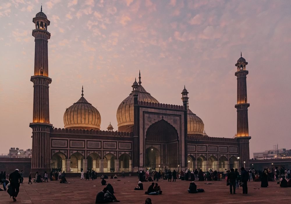 A large mosque courtyard at dusk with people crossing it