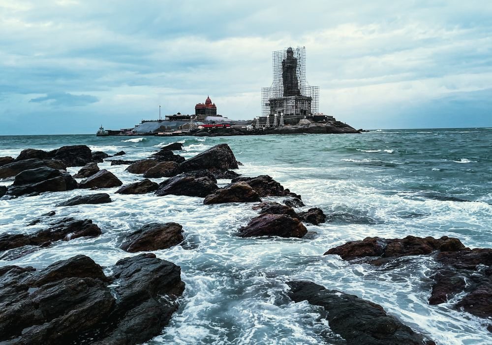 A rocky shoreline with a monument on an island offshore