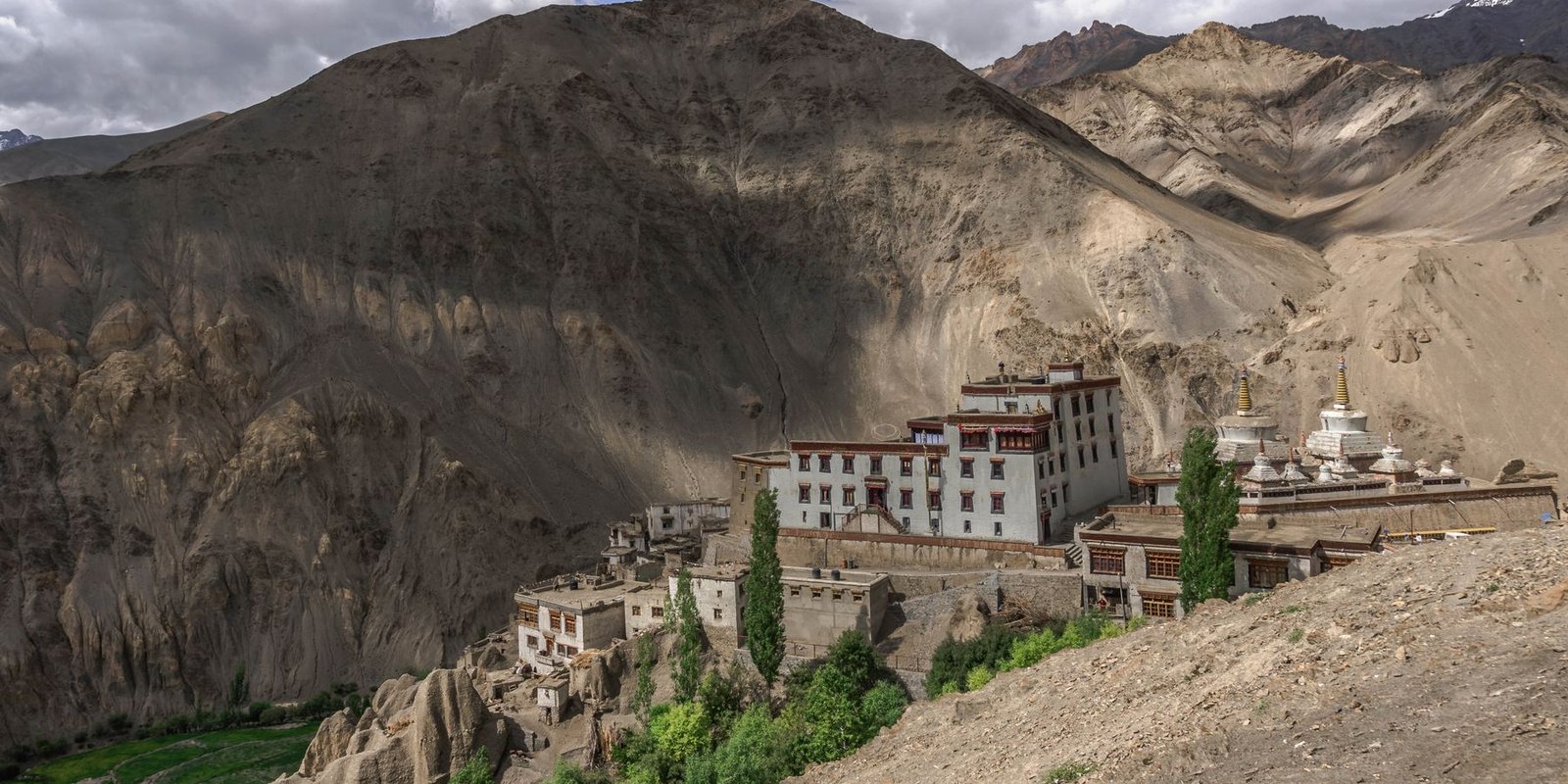 A Ladakhi monastery built into a brown hillside above the valley