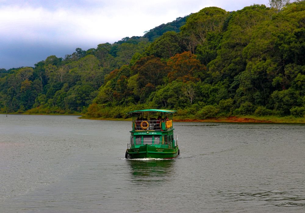 A boat crossing the lake at Periyar with forest behind