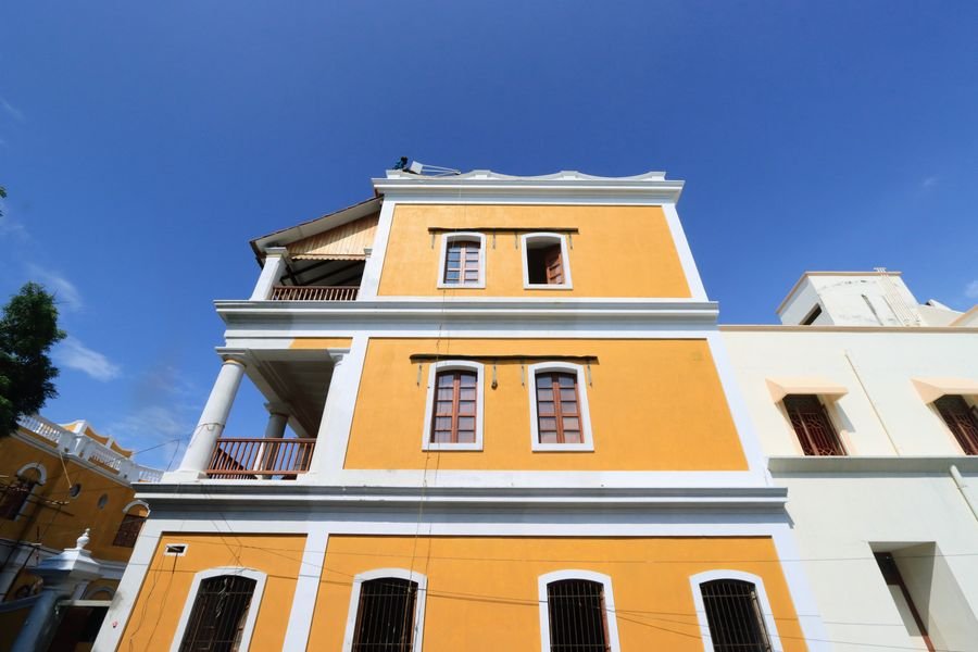 A yellow colonial building with shuttered windows