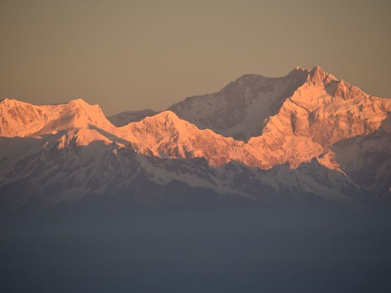 Snow peaks lit orange at sunrise in the eastern Himalaya